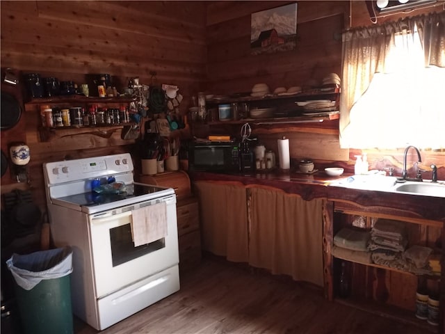 kitchen with white range with electric cooktop, sink, wooden walls, and hardwood / wood-style floors