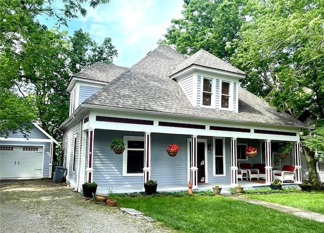 view of front of property featuring a garage, a front yard, an outdoor structure, and a porch