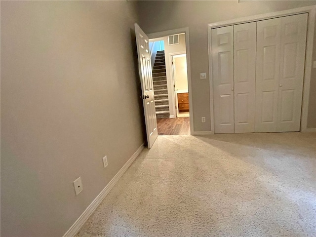 unfurnished bedroom featuring light carpet and a closet