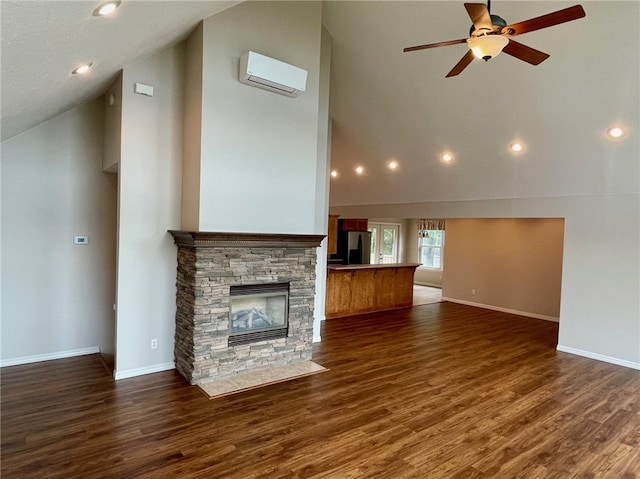 unfurnished living room with a fireplace, dark hardwood / wood-style flooring, a wall mounted AC, and high vaulted ceiling