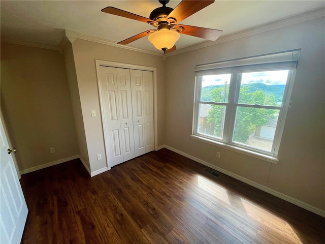 unfurnished bedroom with ceiling fan, ornamental molding, a closet, and dark hardwood / wood-style flooring