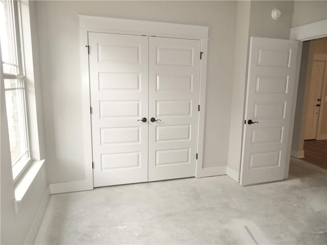 unfurnished bedroom featuring baseboards, a closet, and unfinished concrete floors