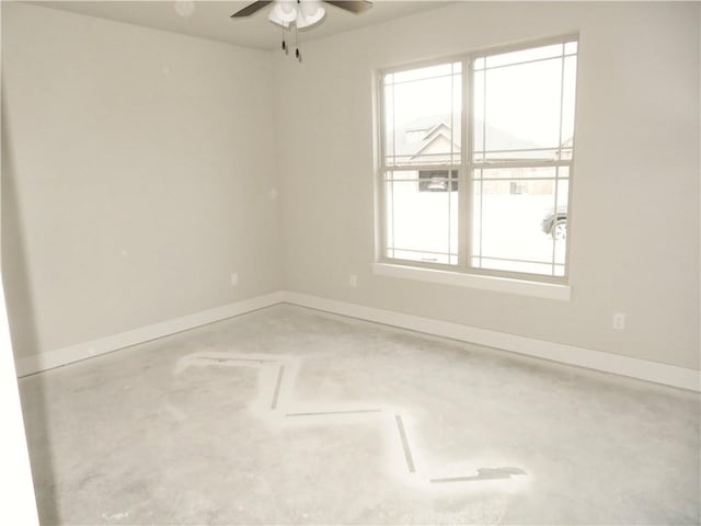 empty room with concrete flooring, baseboards, and a ceiling fan