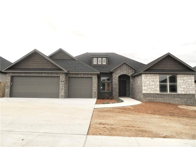 view of front of house featuring a garage, driveway, brick siding, and roof with shingles