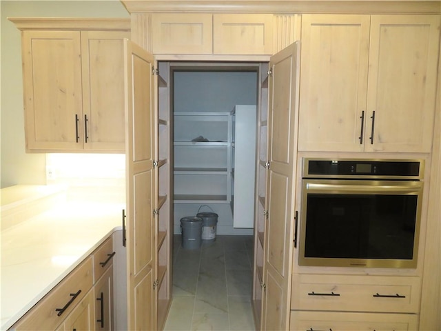 kitchen with light brown cabinets, stainless steel oven, and light countertops