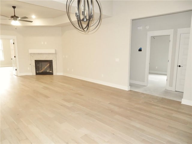 unfurnished living room with light wood-type flooring, a high end fireplace, and baseboards