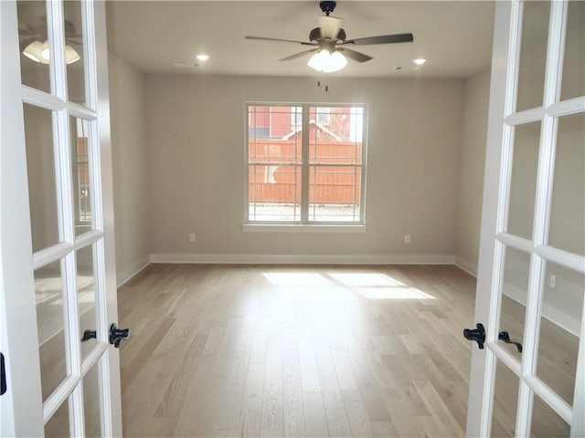 empty room with french doors, baseboards, and light wood finished floors