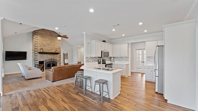 kitchen featuring appliances with stainless steel finishes, a breakfast bar, a fireplace, white cabinetry, and kitchen peninsula