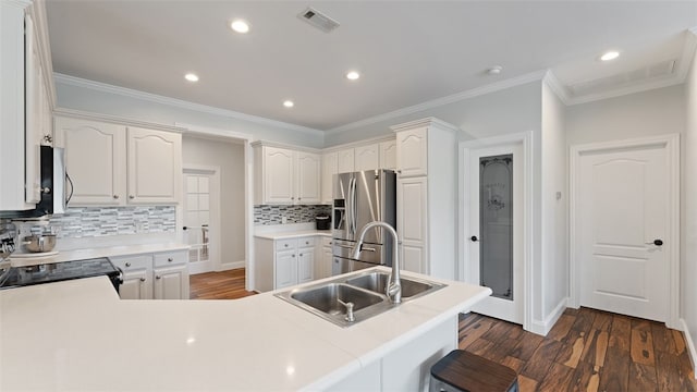 kitchen with sink, appliances with stainless steel finishes, white cabinetry, dark hardwood / wood-style flooring, and kitchen peninsula