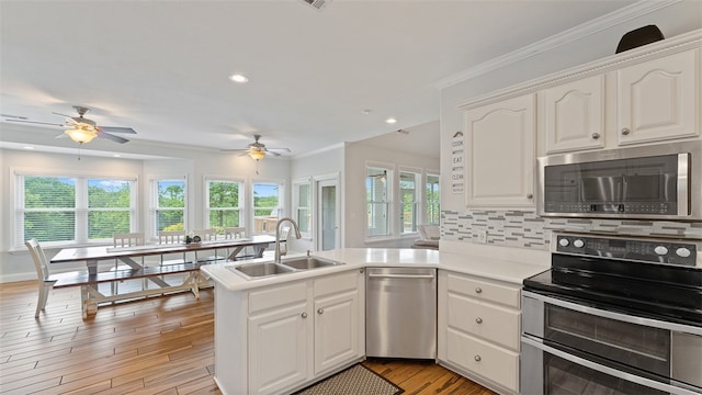 kitchen with appliances with stainless steel finishes, sink, white cabinets, and kitchen peninsula