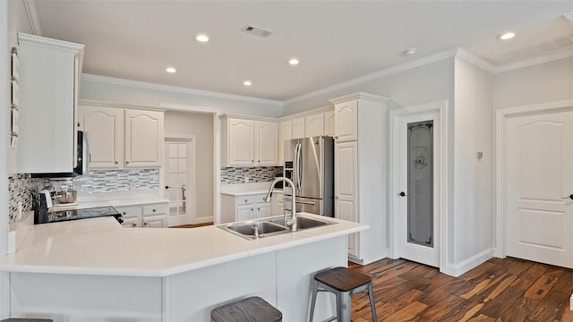 kitchen featuring sink, dark wood-type flooring, a breakfast bar area, appliances with stainless steel finishes, and kitchen peninsula