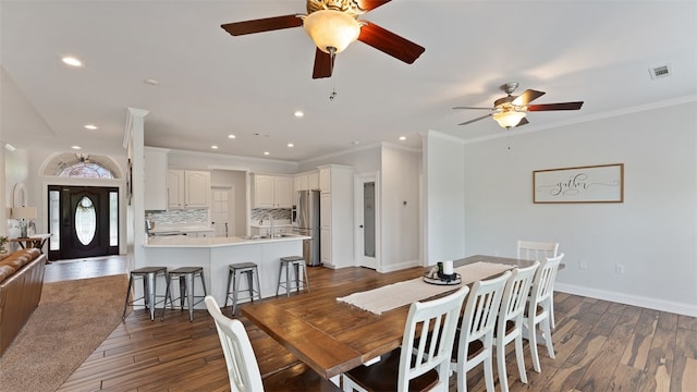 dining area with crown molding, dark hardwood / wood-style floors, sink, and ceiling fan