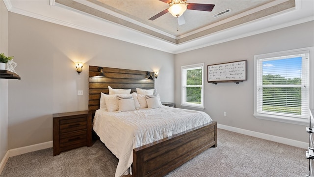 carpeted bedroom featuring a tray ceiling, ornamental molding, and ceiling fan