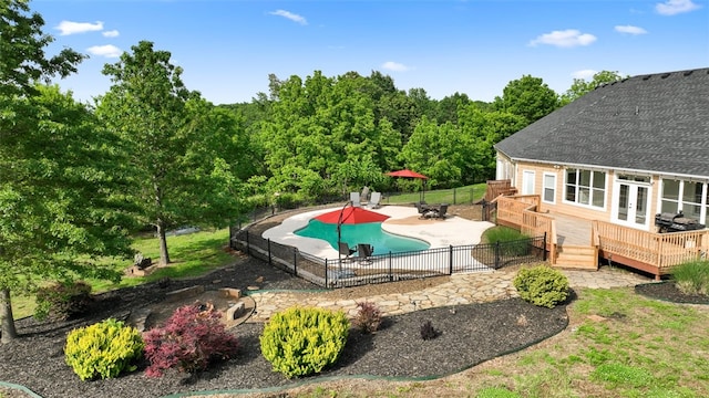 view of pool featuring a wooden deck, an outbuilding, and a patio area