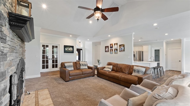 living room with french doors, sink, high vaulted ceiling, ornamental molding, and a fireplace