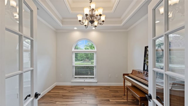 misc room with wood-type flooring, a chandelier, crown molding, and a tray ceiling