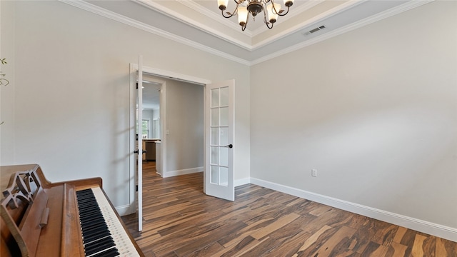 interior space with an inviting chandelier, dark hardwood / wood-style flooring, ornamental molding, and a raised ceiling