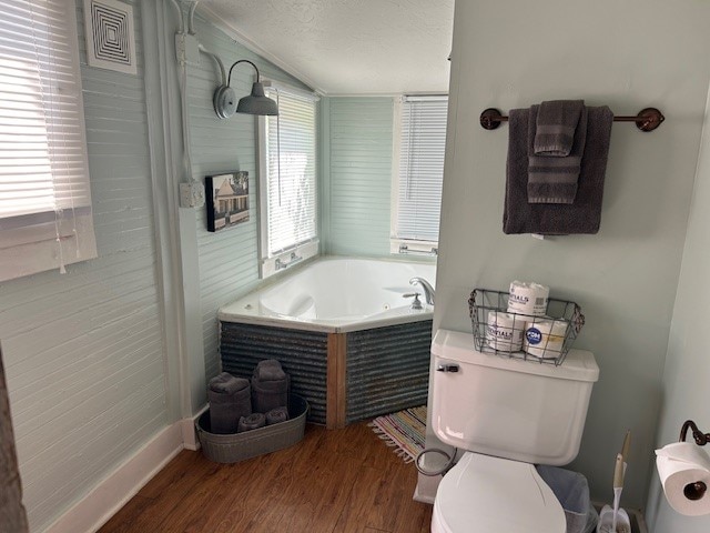 bathroom featuring hardwood / wood-style flooring, a textured ceiling, toilet, and a bathing tub