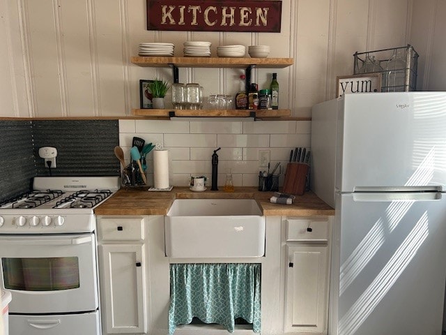 kitchen with white cabinets, white appliances, and backsplash