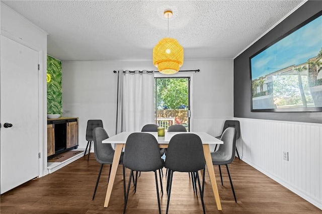 dining space featuring a wainscoted wall, a textured ceiling, and wood finished floors