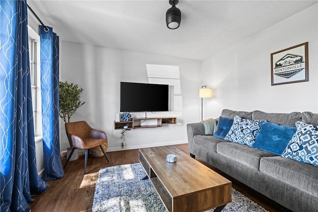 living room with a textured ceiling, wood finished floors, and baseboards