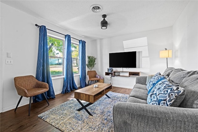 living area with visible vents, dark wood finished floors, a textured ceiling, and baseboards