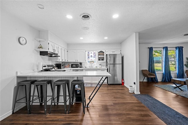 kitchen with stainless steel appliances, visible vents, a peninsula, and open shelves