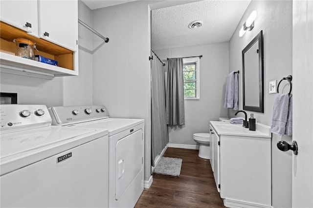 clothes washing area featuring dark wood finished floors, visible vents, a textured ceiling, washer and dryer, and laundry area