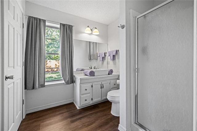 full bath featuring plenty of natural light, a shower stall, a textured ceiling, and wood finished floors