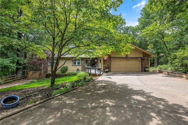 view of front of property featuring concrete driveway, an attached garage, and fence