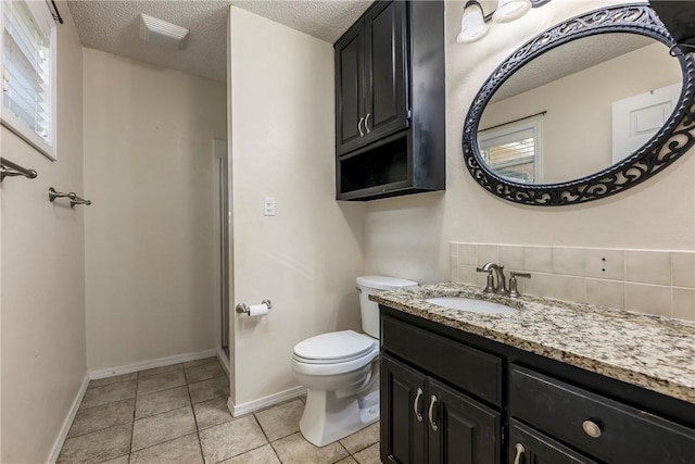 bathroom featuring toilet, a textured ceiling, vanity, tile patterned flooring, and baseboards