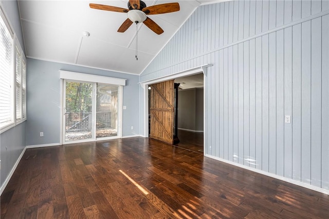 unfurnished room with a ceiling fan, dark wood-style flooring, vaulted ceiling, and a barn door