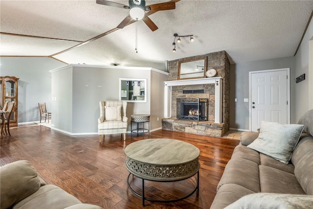 living area featuring a stone fireplace, vaulted ceiling, a textured ceiling, and wood finished floors