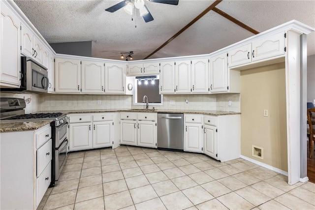 kitchen featuring tasteful backsplash, appliances with stainless steel finishes, white cabinets, a sink, and dark stone countertops