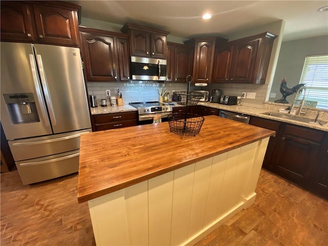 kitchen featuring stainless steel appliances, a center island, butcher block countertops, and dark brown cabinets