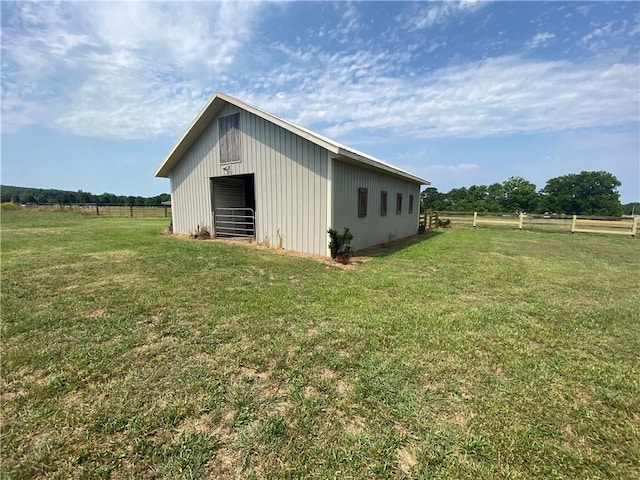 view of side of home featuring an outbuilding, a lawn, and a rural view