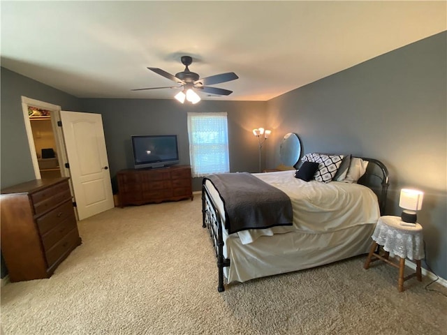 bedroom featuring a walk in closet, light carpet, and ceiling fan