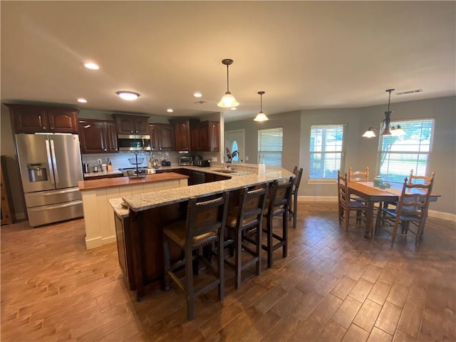 kitchen featuring hanging light fixtures, a kitchen bar, kitchen peninsula, and appliances with stainless steel finishes