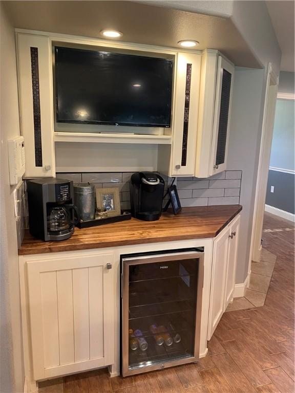 bar featuring wood counters, white cabinetry, beverage cooler, and decorative backsplash