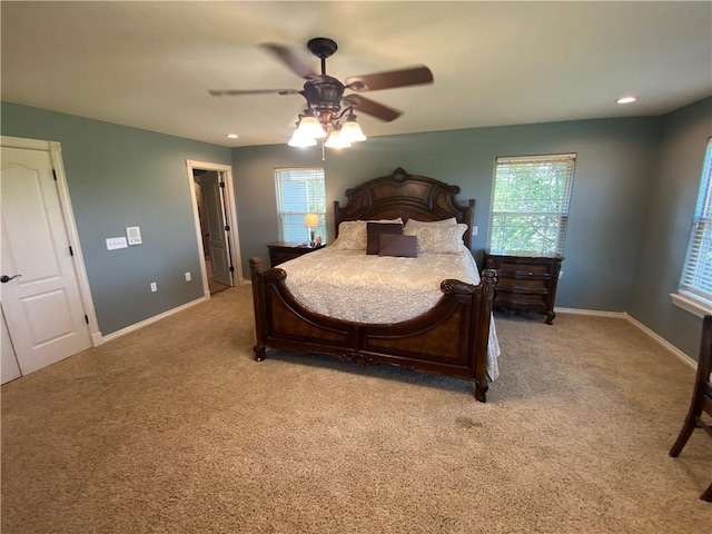 bedroom featuring multiple windows, light colored carpet, and ceiling fan