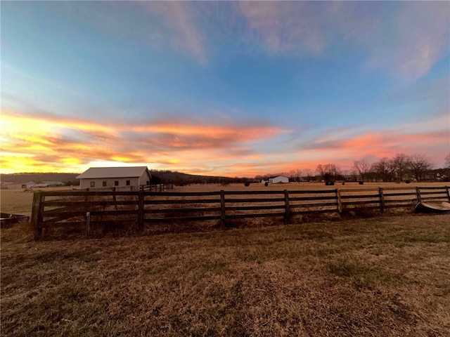 yard at dusk featuring a rural view