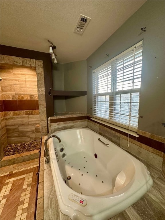 bathroom featuring tiled bath and a textured ceiling