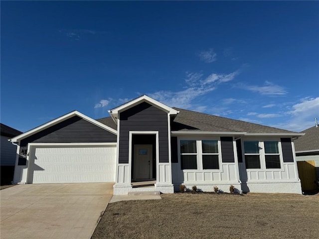 view of front of house with a garage, concrete driveway, a front lawn, and a shingled roof