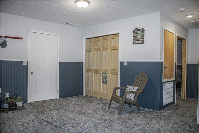 sitting room featuring dark colored carpet and a textured ceiling