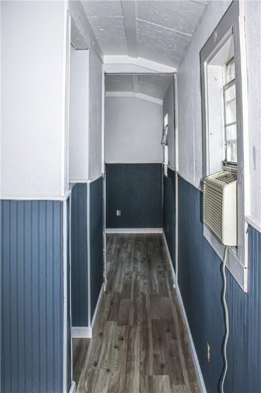 corridor with wood walls, dark hardwood / wood-style flooring, and vaulted ceiling