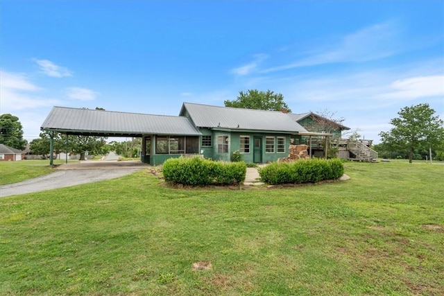 ranch-style home with driveway, metal roof, an attached carport, and a front yard