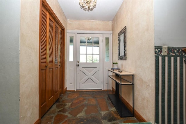 doorway to outside featuring a textured wall and stone tile flooring