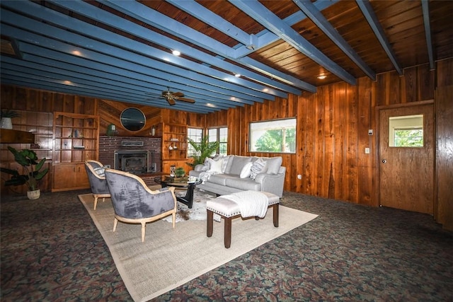 living area featuring plenty of natural light, carpet flooring, beamed ceiling, and wooden walls