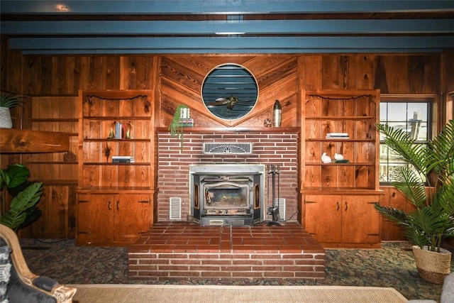 living room with visible vents, wood walls, brick floor, and a wood stove