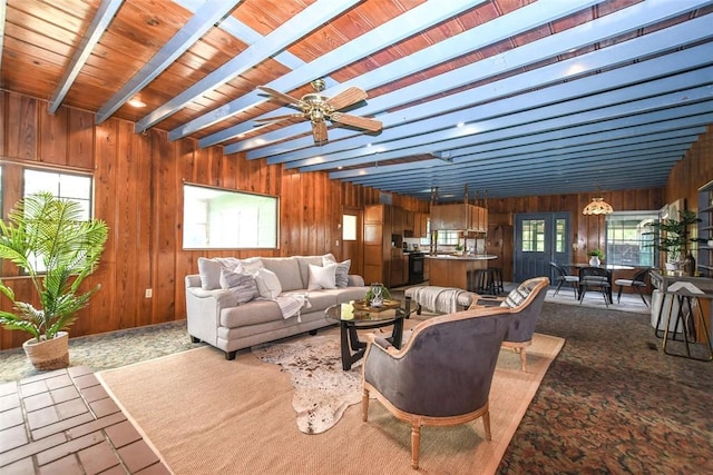 living room featuring ceiling fan, wooden walls, and beam ceiling